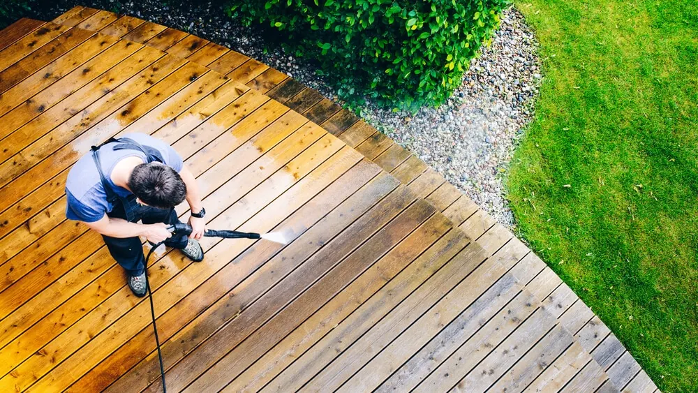 Overhead view of a worker pressure washing a wooden deck