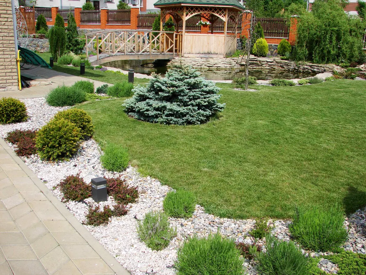 Landscaped garden with a gazebo, stone path, shrubs, and a lawn