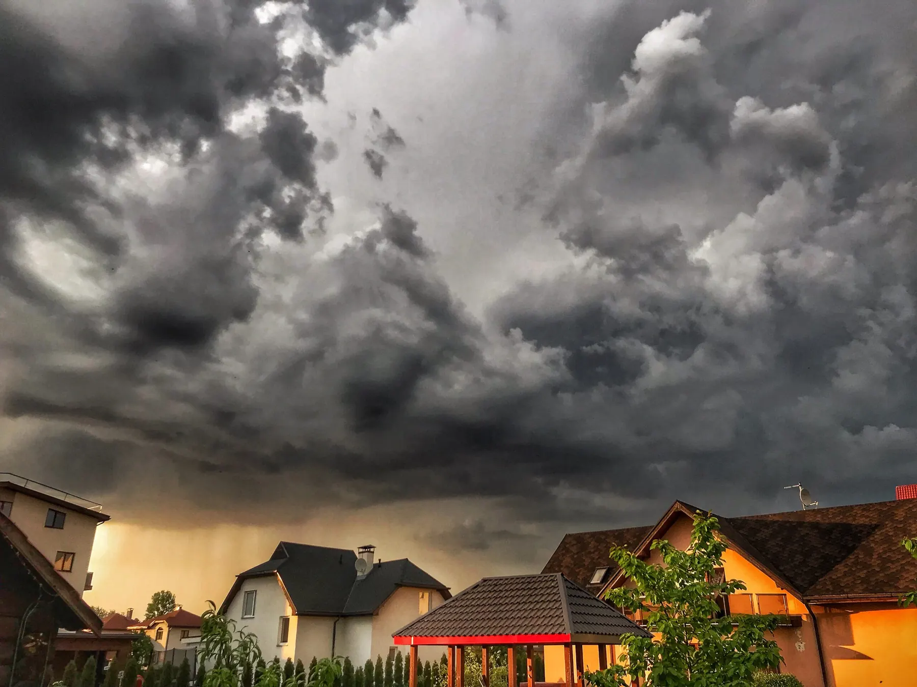 Dark storm clouds gathering over a row of rooftops at dusk
